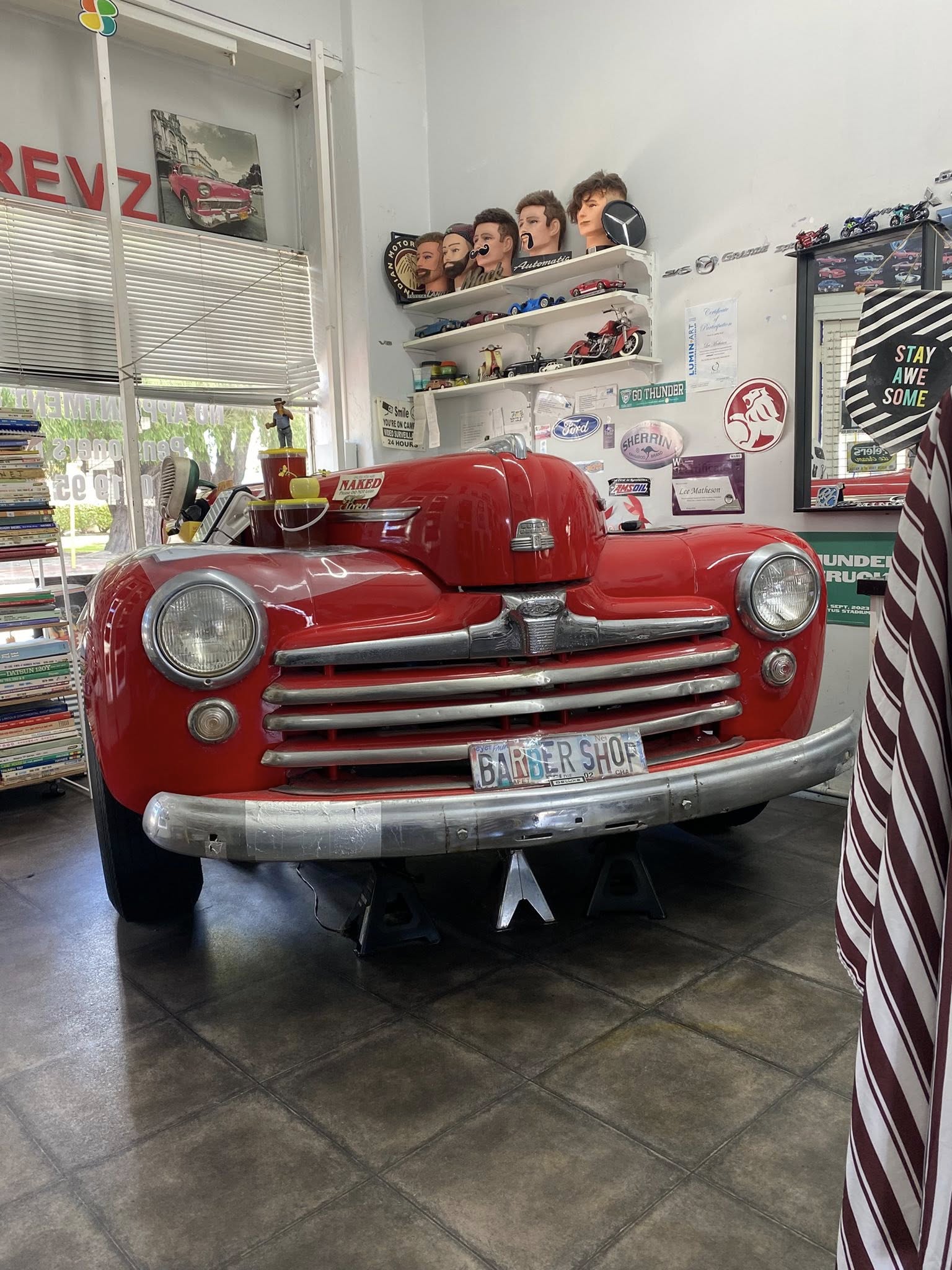 Classic red hot-rod inside Revz Barber Shop with a BARBER SHOP plate